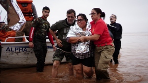 Firefighters help residents evacuate from an area flooded by heavy rains in Porto Alegre, Rio Grande do Sul state, Brazil, Saturday, May 4, 2024. (AP Photo/Carlos Macedo)