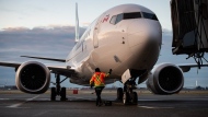 A ground worker approaches a WestJet Airlines Boeing 737 Max aircraft after it arrived at Vancouver International Airport in Richmond, B.C., on Thursday, January 21, 2021. WestJet has issued a 72-hour lockout notice to the union representing its mechanics, and warns a work stoppage could happen as early as Tuesday. THE CANADIAN PRESS/Darryl Dyck