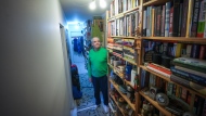 John William, who is losing his sight, poses for a photograph with his collection of books that he has decided to sell, in Vancouver, on Wednesday, April 24, 2024. (Darryl Dyck / The Canadian Press) 