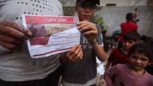 Palestinians hold leaflets dropped by Israeli planes calling on them to evacuate ahead of an Israeli military operation in Rafah, southern Gaza Strip, Monday, May 6, 2024. (AP Photo/Ismael Abu Dayyah)