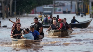 Volunteers help to evacuate residents from an area flooded by heavy rains, in Porto Alegre, Brazil, Tuesday, May 7, 2024. (AP Photo/Andre Penner)