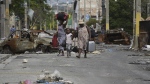 Residents walk past a burnt car blocking the street as they evacuate the Delmas 22 neighborhood to escape gang violence in Port-au-Prince, Haiti, Thursday, May 2, 2024. THE CANADIAN PRESS/AP-Ramon Espinosa