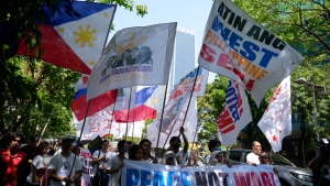 Protesters hold slogans during a rally outside the Chinese consulate in Makati, Philippines on Friday, April 19, 2024. (AP Photo/Aaron Favila)
