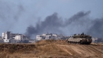 Backdropped by smoke rising to the sky after an explosion in the Gaza Strip, an Israeli tank stands near the Israel-Gaza border as seen from southern Israel, Monday, May 13, 2024. (AP Photo/Leo Correa)