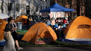 Passersby walk past tents at an encampment of students protesting against the war in Gaza, in Harvard Yard, at Harvard University in Cambridge, Mass., on Thursday, April 25, 2024. (AP Photo/Ben Curtis) 