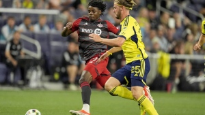 Toronto FC forward Deandre Kerr, left, and Nashville SC defender Walker Zimmerman (25) chase the ball during the first half of an MLS soccer match Wednesday, May 15, 2024, in Nashville, Tenn. THE CANADIAN PRESS/AP-George Walker IV