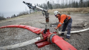 Justin Massie, wildfire specialist with Fire & Flood Emergency Service Ltd., adjusts a valve on a wildfire suppression water cannon along Highway 881 near Gregoire Lake Estates southeast of Fort McMurray, Wednesday, May 15, 2024.THE CANADIAN PRESS/Jeff McIntosh