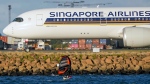 A man wing foils on Botany Bay as a Singapore Airlines passenger jet taxis after landing at Sydney Airport in Australia, Monday, Sept. 5, 2022. (AP Photo/Mark Baker)