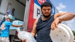 FILE - Daniel Valdez places a fresh bag of ice in a cooler he brought on foot from his apartment as volunteers at the Memorial Assistance Ministries distribute water and ice, Saturday, May 18, 2024, in Houston. Extreme heat in Mexico, Central America and parts of the U.S. South has left millions of people sweltering, strained energy grids and resulted in iconic Howler monkeys in Mexico dropping dead from trees. (Jason Fochtman/Houston Chronicle via AP, File)