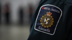 A patch is seen on the shoulder of a Canada Border Services Agency officer's uniform as he listens during an announcement in Tsawwassen, B.C., Friday, Dec. 16, 2022. THE CANADIAN PRESS/Darryl Dyck