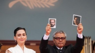 Director Mohammad Rasoulof holds up photographs of actors Soheila Golestani, right, and Missagh Zareh alongside Soheila Golestani, left, upon arrival at the premiere of the film 'The Seed of the Sacred Fig' at the 77th international film festival, Cannes, southern France, Friday, May 24, 2024. (Photo by Scott A Garfitt/Invision/AP)