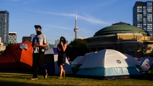 People walk through a pro-Palestinian encampment set up at the University of Toronto campus, in Toronto on Friday, May 24, 2024. (THE CANADIAN PRESS/Christopher Katsarov)