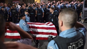 Law enforcement officers salute the flag-draped remains of fallen officer Jamal Mitchell as he is escorted to a waiting medical examiner's vehicle outside Hennepin County Medical Center in Minneapolis, Thursday, May 30, 2024. (Aaron Lavinsky/Star Tribune via AP)