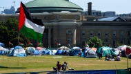 A Palestinian flag flies over the pro-Palestinian encampment set up in front of Convocation Hall at the University of Toronto campus, in Toronto, Sunday, May 26, 2024. Toronto police say they will only take action to clear the encampment at the University of Toronto in case of emergency or to carry out a court order.THE CANADIAN PRESS/Frank Gunn
