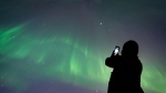 The northern lights could return to the sky over parts of Canada as a sunspot that contributed to a recent stunning aurora display rotates back Earth-side. A person takes a photo of the northern lights in Vancouver, on Saturday, May 11, 2024. THE CANADIAN PRESS/Ethan Cairns