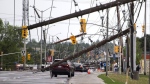 A vehicle is seen among downed power lines and utility poles after a major storm on Merivale Road in Ottawa on Saturday, May 21, 2022.  THE CANADIAN PRESS/Justin Tang