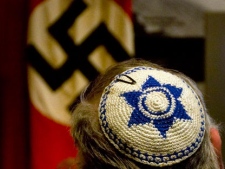 A Jewish man looks at exhibit showing the Nazi flag, during a visit at Yad Vashem Holocaust Memorial in Jerusalem Sunday, April 11, 2010. The annual Israeli memorial day for the 6 million Jews killed in the Holocaust of World War II begins at sundown Sunday. (AP Photo/Sebastian Scheiner)