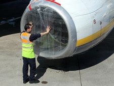 A aircraft maintenance worker covers a jet engine intake at Belfast City Airport, Northern Ireland, Friday, April, 16, 2010. (AP Photo/Peter Morrison) 