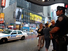 A New York City police officer stands watch on Times Square in New York, Monday, May 3, 2010, as pedestrians pass by. Activity appeared normal in the wake of a car bomb incident over the weekend. (AP Photo/Craig Ruttle)