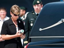 The wife of Col. Geoff Parker places a can of beer into the hearse where his casket Parker rests at CFB Trenton on Friday, May 21, 2010 in Trenton, Ont. 