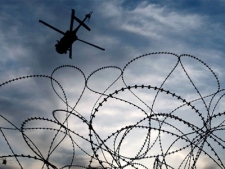 A military helicopter is seen through razor wire as it comes in to land at Kandahar Air Field, southern Afghanistan Sunday, Jan. 31, 2010. (AP / Kirsty Wigglesworth)