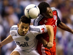 Vancouver Whitecaps player Davide Chiumiento, left, and Toronto FC's Julian de Guzman jump for the ball during the second half of a Canadian Championship soccer game in Vancouver, B.C., on Wednesday, May 16, 2012. (THE CANADIAN PRESS/Darryl Dyck)