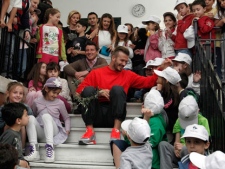 Former England football captain David Beckham, front, and London Olympic chairman Sebastian Coe sit with students at the Athens University experimental primary school, in Athens, Friday, May 18, 2012, a day after the ceremonial handover of the Olympic flame to the organizers of the 2012 London Olympics. (AP Photo/Petros Giannakouris)