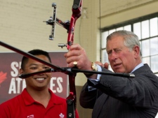 Prince Charles tries out a bow while touring the future site of the Pan/Parapan American Games Athlete's Village in Toronto on Tuesday, May 22, 2012. (THE CANADIAN PRESS/Paul Chiasson)