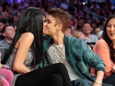 Singer Justin Bieber kisses actress Selena Gomez during the first half of an NBA basketball game as the San Antonio Spurs play the Los Angeles Lakers on Tuesday, April 17, 2012, in Los Angeles. (AP Photo/Jason Redmond)