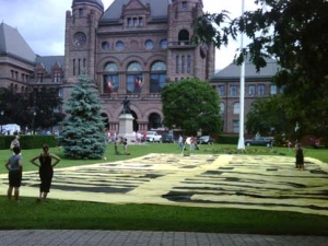 First Nations activists lay down a large banner on the grounds of Queen's Park on June 24, 2010 ahead of a protest.