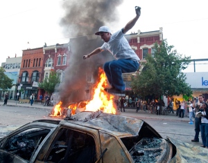 A protester jumps on a burnt out car as a police car burns in the background during an anti-G20 demonstration Saturday, June 26, 2010 in Toronto. (THE CANADIAN PRESS/Ryan Remiorz)