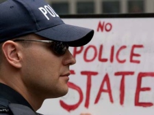 A police officer looks on in front of a placard during a demonstration as the G20 summit draws to a close in Toronto, Sunday, June 27, 2010. (Chris Young/THE CANADIAN PRESS)