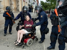 RCMP riot squad officers escort a woman in a wheelchair away from a demonstration at the conclusion of the G20 summit in Toronto on Sunday, June 27, 2010. (THE CANADIAN PRESS/Frank Gunn)