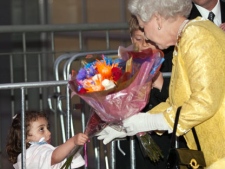 Three-year-old Melanie Samson reaches through a fence to give The Queen a bouquet of flowers following a cultural performance Tuesday, June 29, 2010 in Halifax. (THE CANADIAN PRESS/Paul Chiasson)