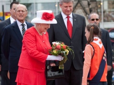 Queen Elizabeth is presented with a bouquet of flowers by Kathie Gibbons as Canadian Prime Minister Stephen Harper and Prince Philip look on prior to Canada Day celebrations on Parliament Hill in Ottawa, Thursday July 1, 2010. (THE CANADIAN PRESS/Adrian Wyld)