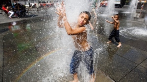 Brothers Mohammed, 10, left, and Yousef Othman, 3, try to cool off while playing in the water fountains at Dundas Square in Toronto on Monday, July 5, 2010. (Darren Calabrese / THE CANADIAN PRESS)