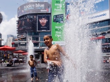 Brothers Mohammed, centre, Yousef, left, and Abdullrahman Othman try to cool off while playing in the water fountains at Dundas Square in Toronto Monday, July 5, 2010. (Darren Calabrese / THE CANADIAN PRESS)