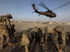 U.S. soldiers shield themselves from the rotor wash of a U.S. Army, 101st Airborne Division, Task Force Destiny medevac helicopter as it takes off with patients, in Zhari district, Kandahar province, southern Afghanistan, Friday, Aug. 20, 2010. (AP Photo/Brennan Linsley)