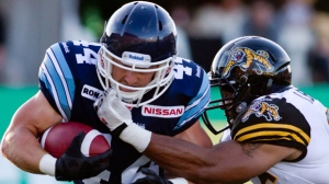 Toronto Argonauts' Chad Kackert, left, is tackled by Hamilton Tiger-Cats' Ike Brown during first half CFL pre-season action in Hamilton on June 13, 2013. (The Canadian Press/ Chris Young)