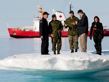Prime Minister Stephen Harper, second from right, stands on an iceberg as he talks with Chief of the Defence Staff General Walter Natynczyk (centre) as they take part in a training exercise during Operation Nanook in Resolute, Nunavut on the third day of his five-day northern tour to Canada's Arctic on Wednesday Aug. 25, 2010. The Canadian Coast Guard's medium icebreaker Henry Larsen is seen in Allen Bay. (THE CANADIAN PRESS/Sean Kilpatrick)