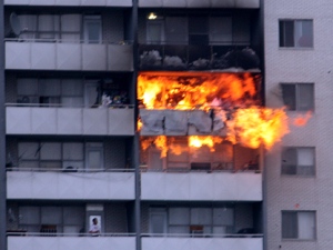 A resident looks up as flames shoot from a 24th floor apartment Friday afternoon. (CP24 MyBreakingNews - Jeff Riffle)