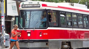 A pedestrian uses a mobile phone while walking in front of a streetcar in downtown Toronto Wednesday, Aug. 3, 2011. (The Canadian Press/Darren Calabrese)
