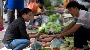 Woman buys vegetables at market in China