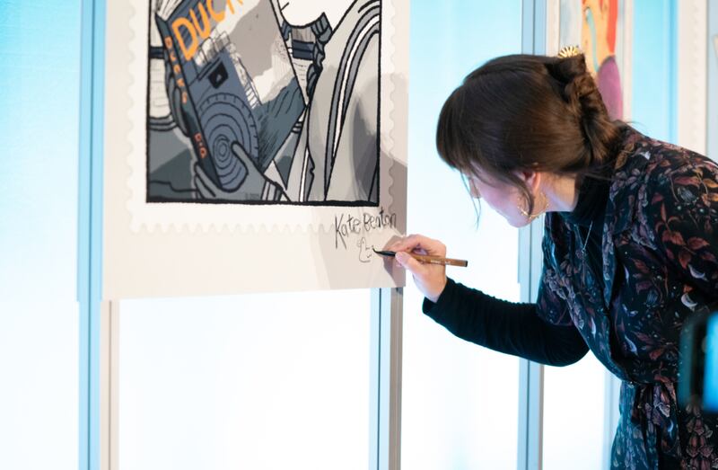 Cartoonist Kate Beaton is pictured signing a photo of a stamp she is feature on. (Courtesy: Canada Post)