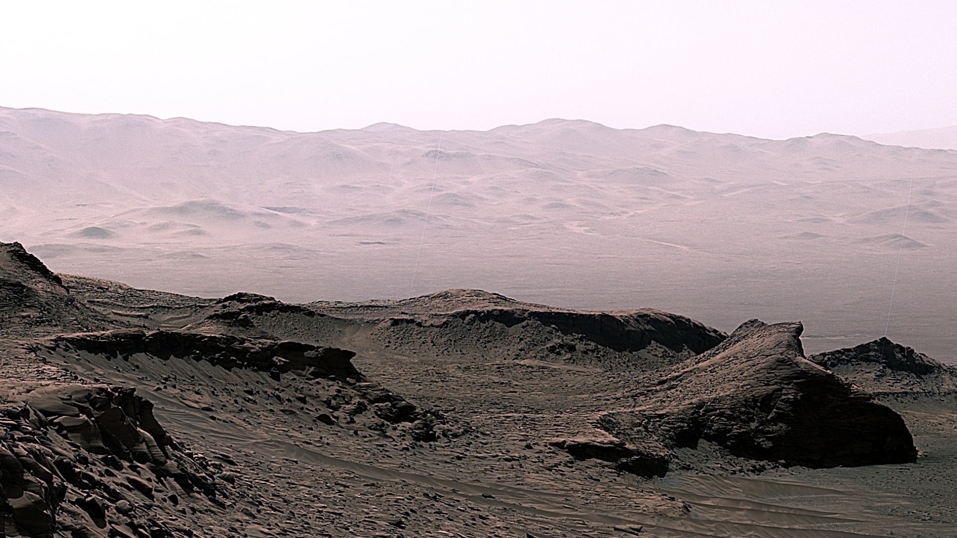 A photomosaic taken by the Curiosity Rover on April 30, 2023, at the Ubajara drill site in Gale Crater, Mars. Rock powder samples drilled here contained substantial amounts of siderite (an iron carbonate mineral). The siderite played a role in ancient carbon cycling processes that impacted conditions at the planet’s surface. Rover tracks in the foreground are 40 cm wide. (Credit: NASA/JPL-Caltech/MSSS)