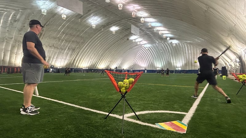Two men play softball indoors.
