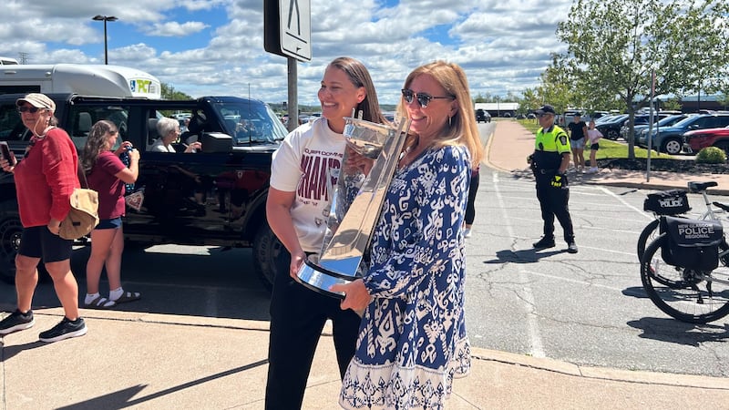 Two women hold a trophy and pose for a photo.