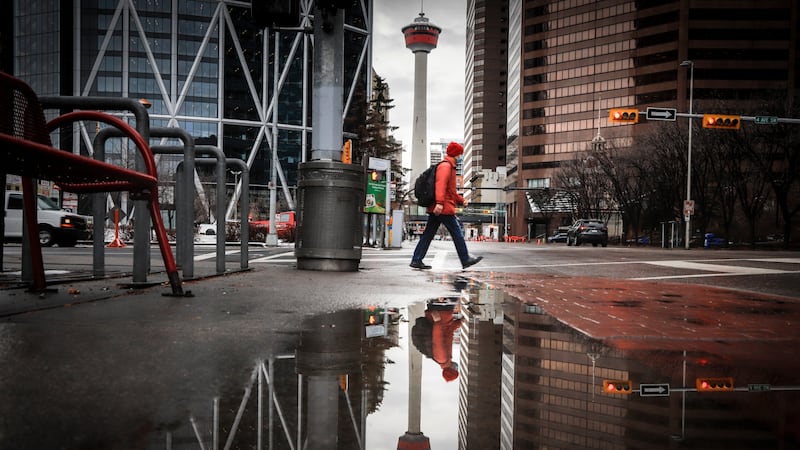 A pedestrian wearing a mask walks through an empty downtown Calgary, Alta., Wednesday, Dec. 9, 2020, after new provincial restrictions were announced amid a worldwide COVID-19 pandemic. THE CANADIAN PRESS/Jeff McIntosh