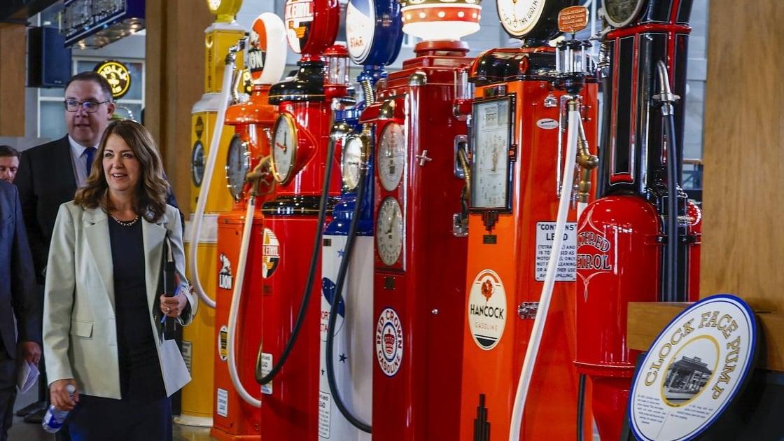 Alberta Premier Danielle Smith, right, walks past antique gas pumps to announce a new affordability measure in Calgary, on Wednesday, June 17, 2026. (THE CANADIAN PRESS/Jeff McIntosh)
