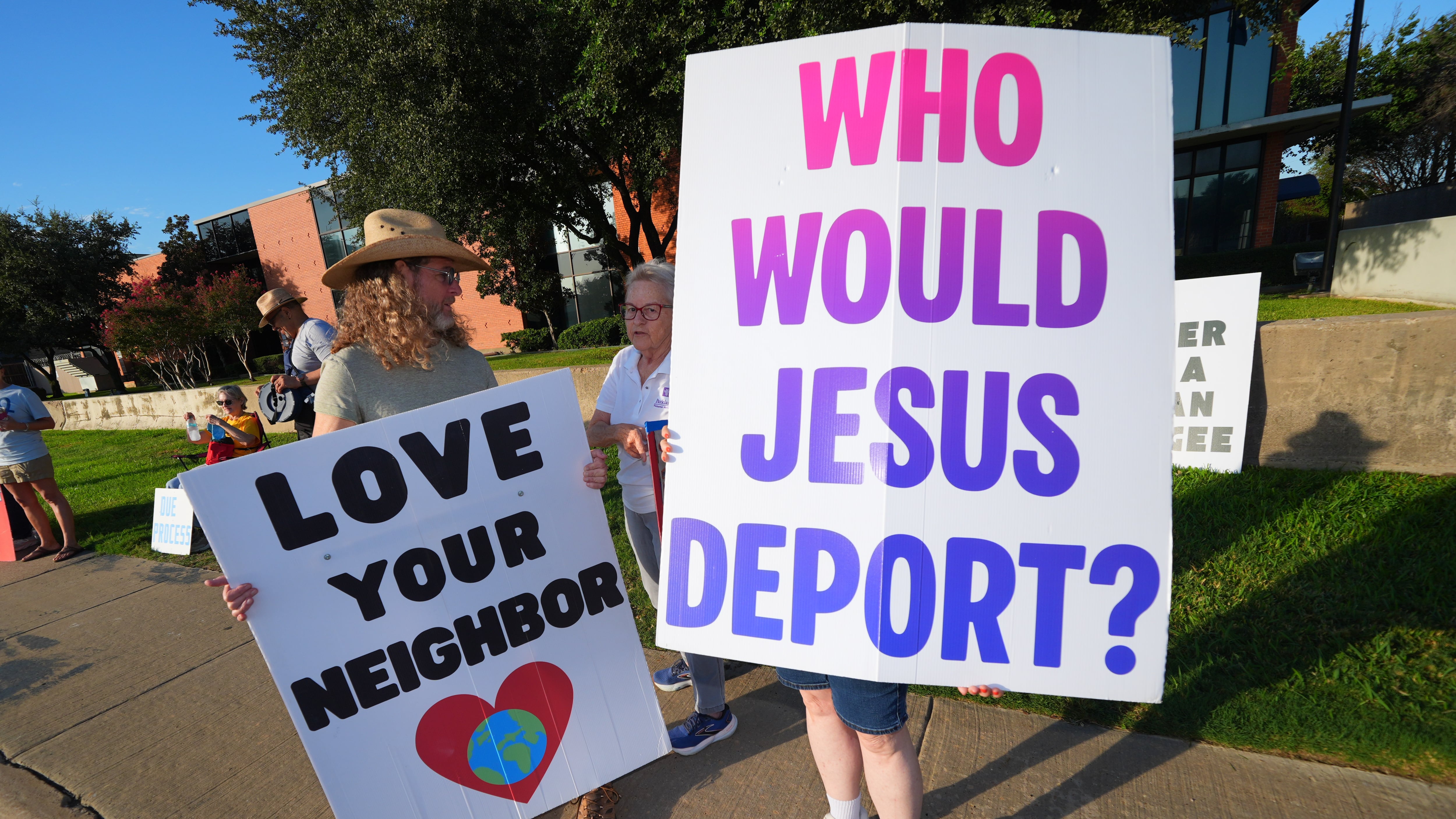 People hold a sign outside the U.S. Immigration and Customs Enforcement (ICE) office during a weekly prayer and protest gathering in Dallas on Oct. 12, 2026. (LM Otero / AP Photo)